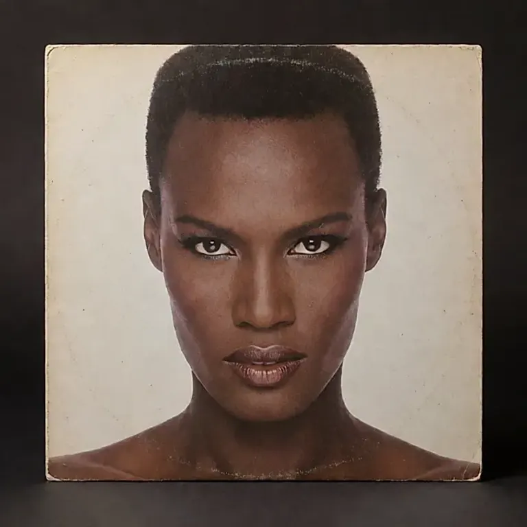 Illustration générée : une pochette de vinyle posée sur fond sombre, éclairée par une lumière douce, avec un coin légèrement usé.